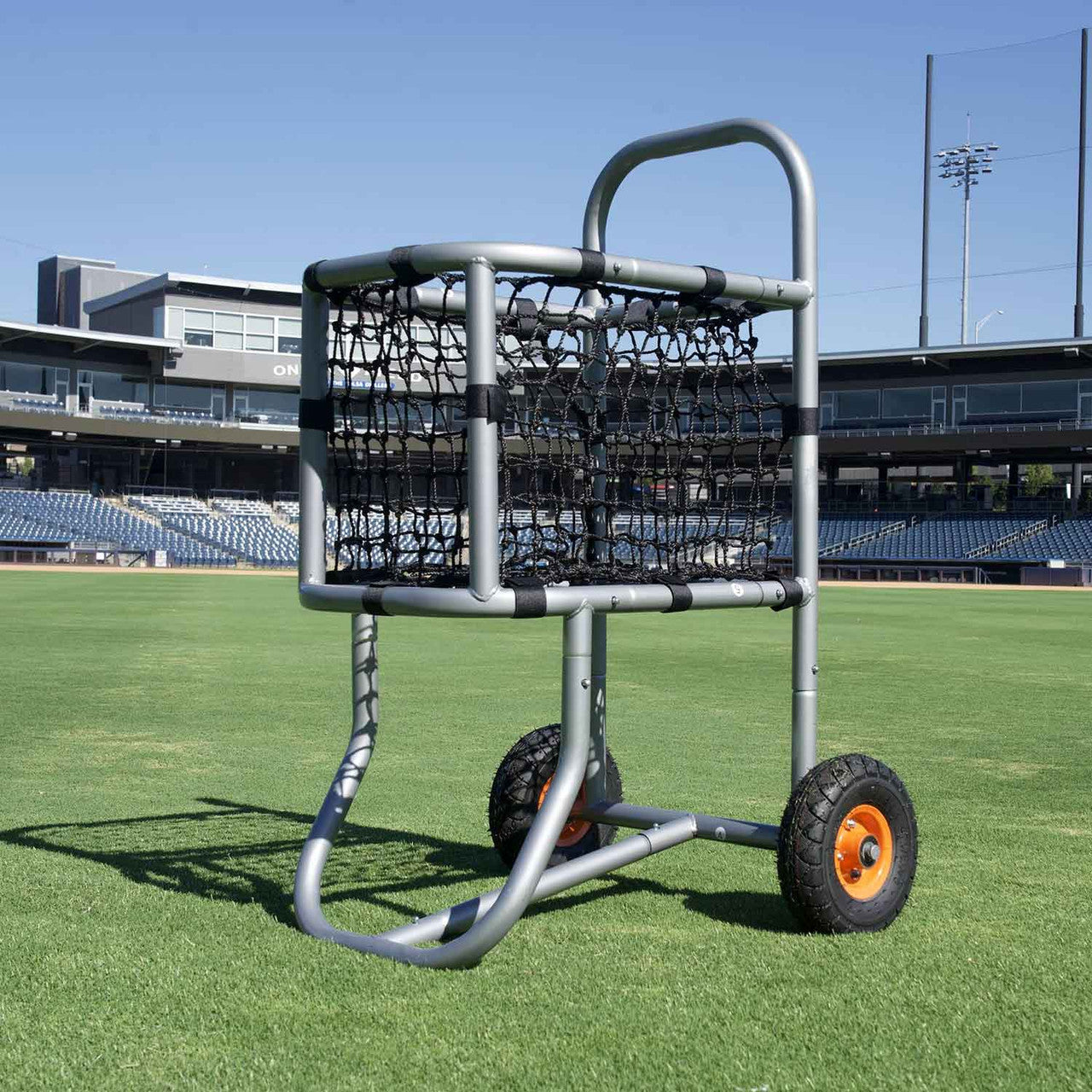 low angle picture of baseball ball cart in center field grass and stadium behind