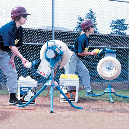 Two Softball players loading balls into pitching machines