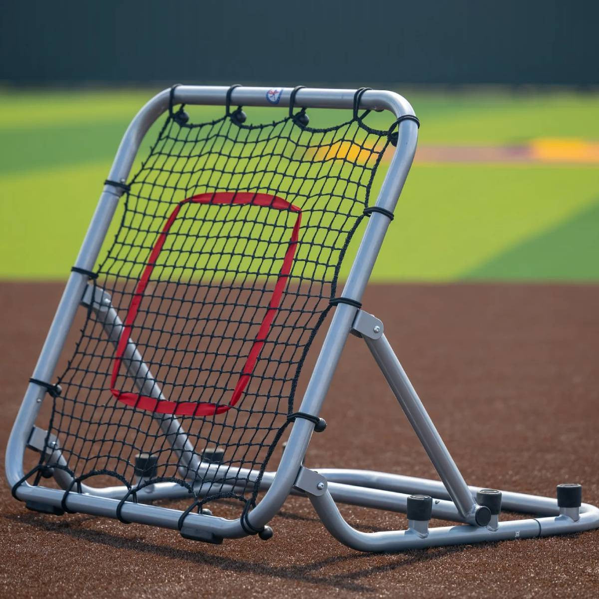 Large rebounder with silver frame and red target on field front angle setup for line drives
